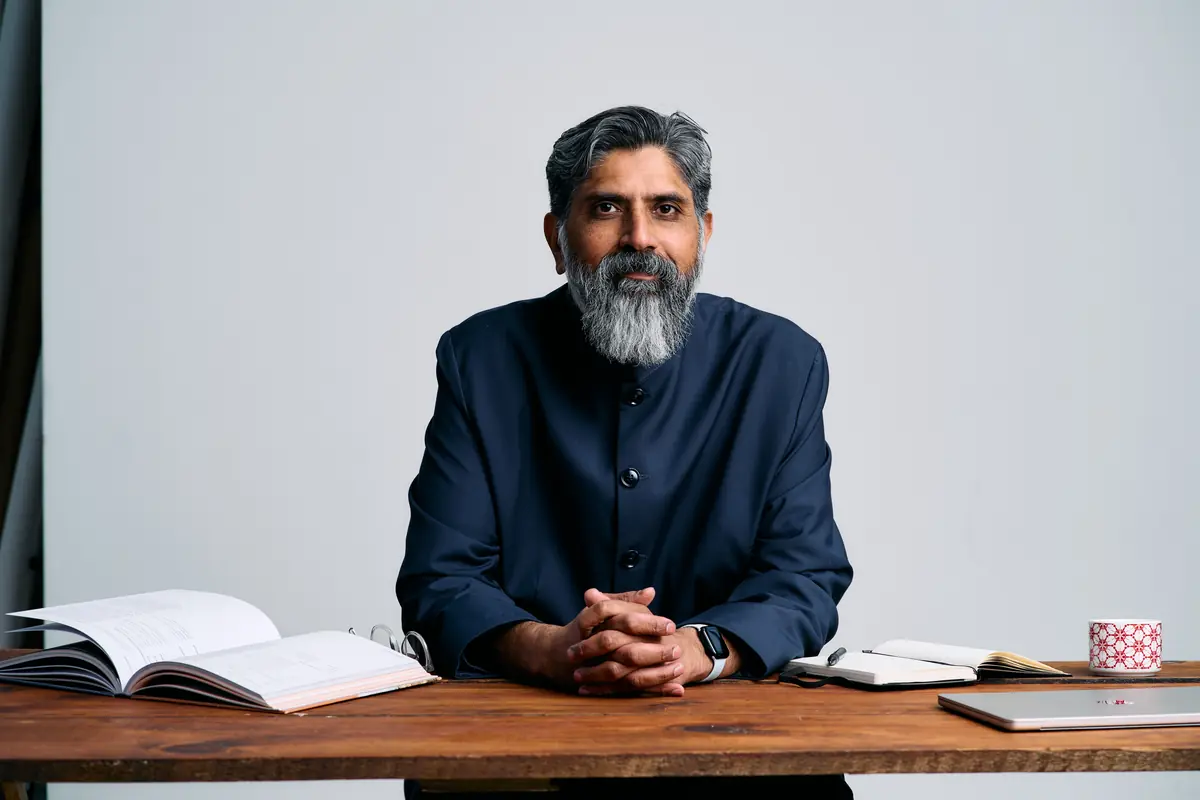 Dr. Yasin Choudry at his desk with an open book. Clinical, considered, calm.