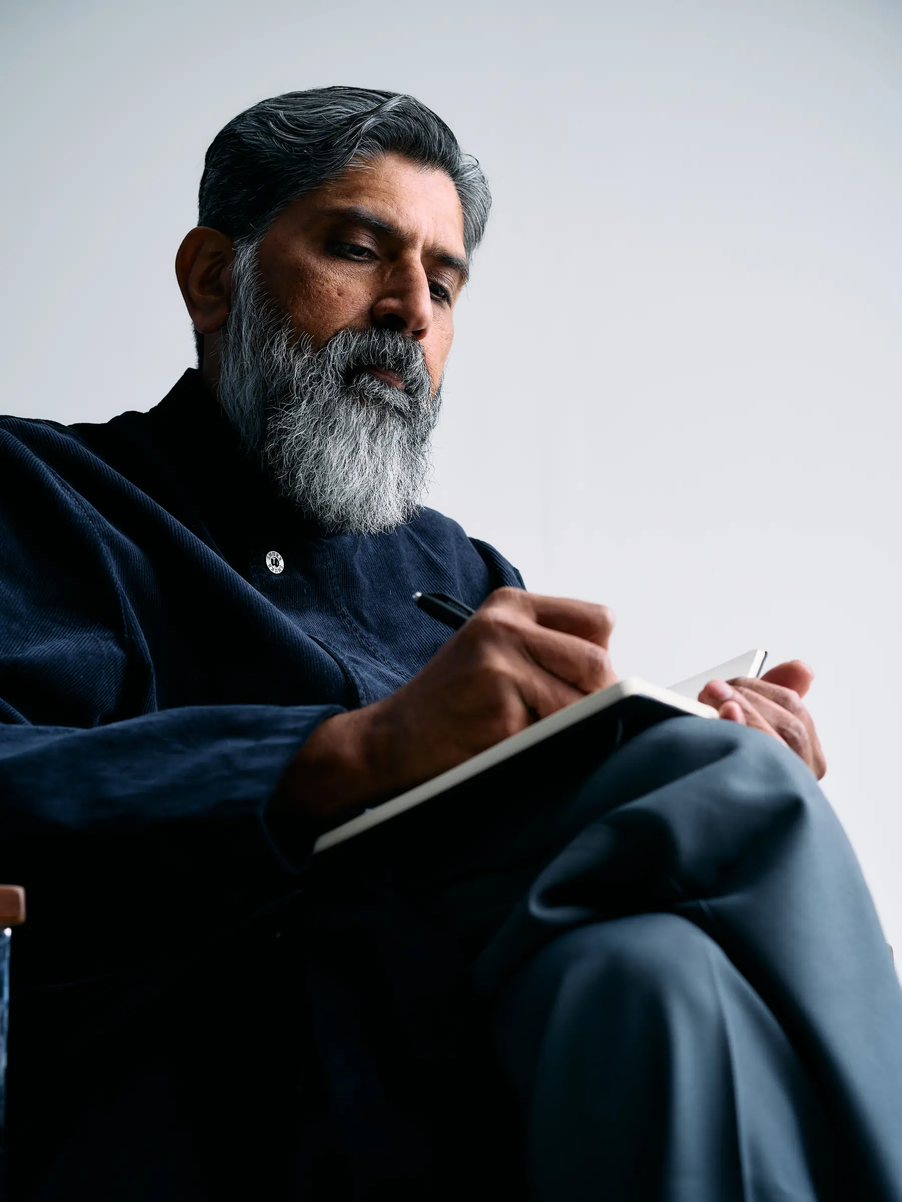 Dr. Yasin Choudry, seated in a dark coat under low, contemplative light.